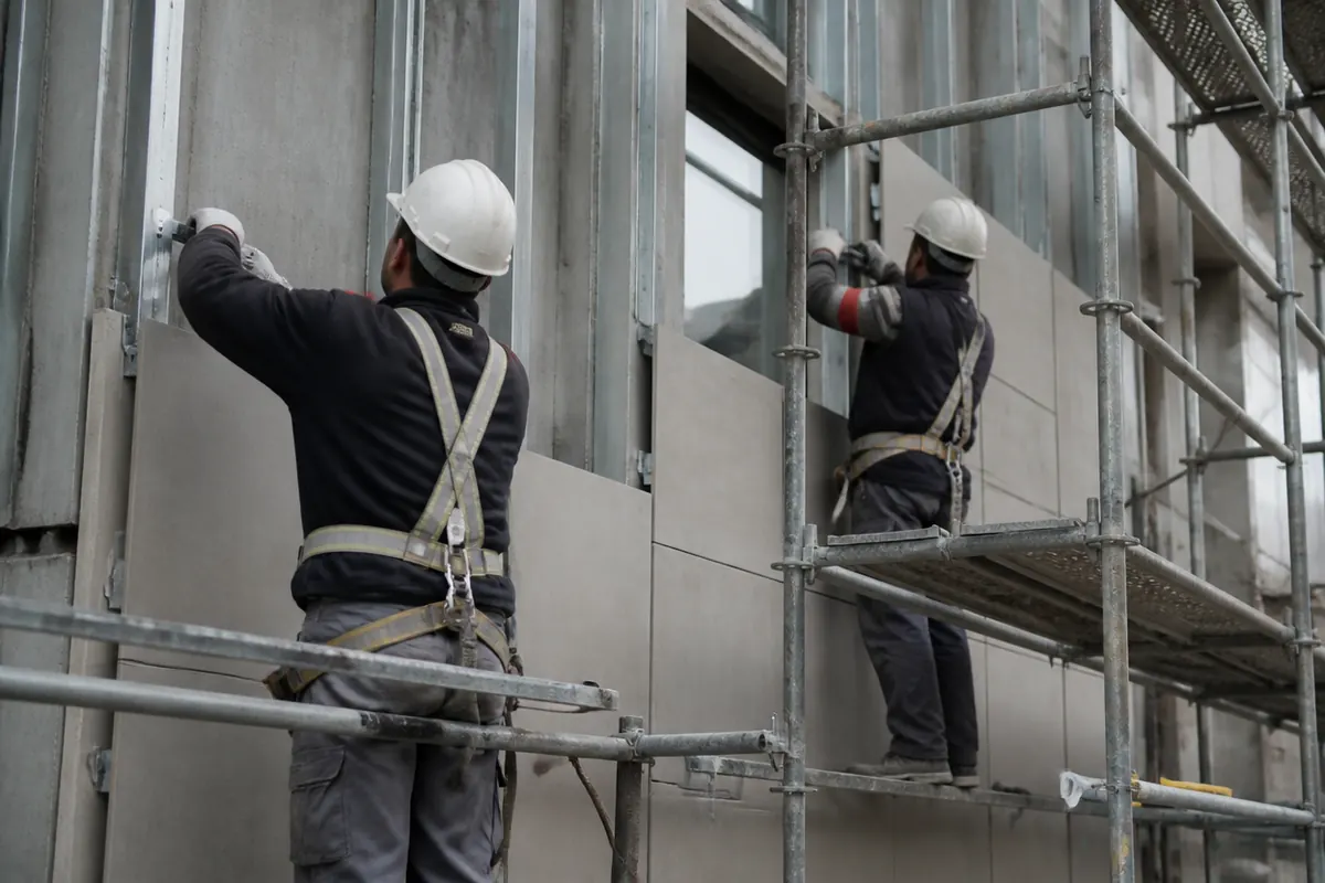 Montaje de subestructura y paneles de fachada ventilada en edificio residencial con andamio perimetral