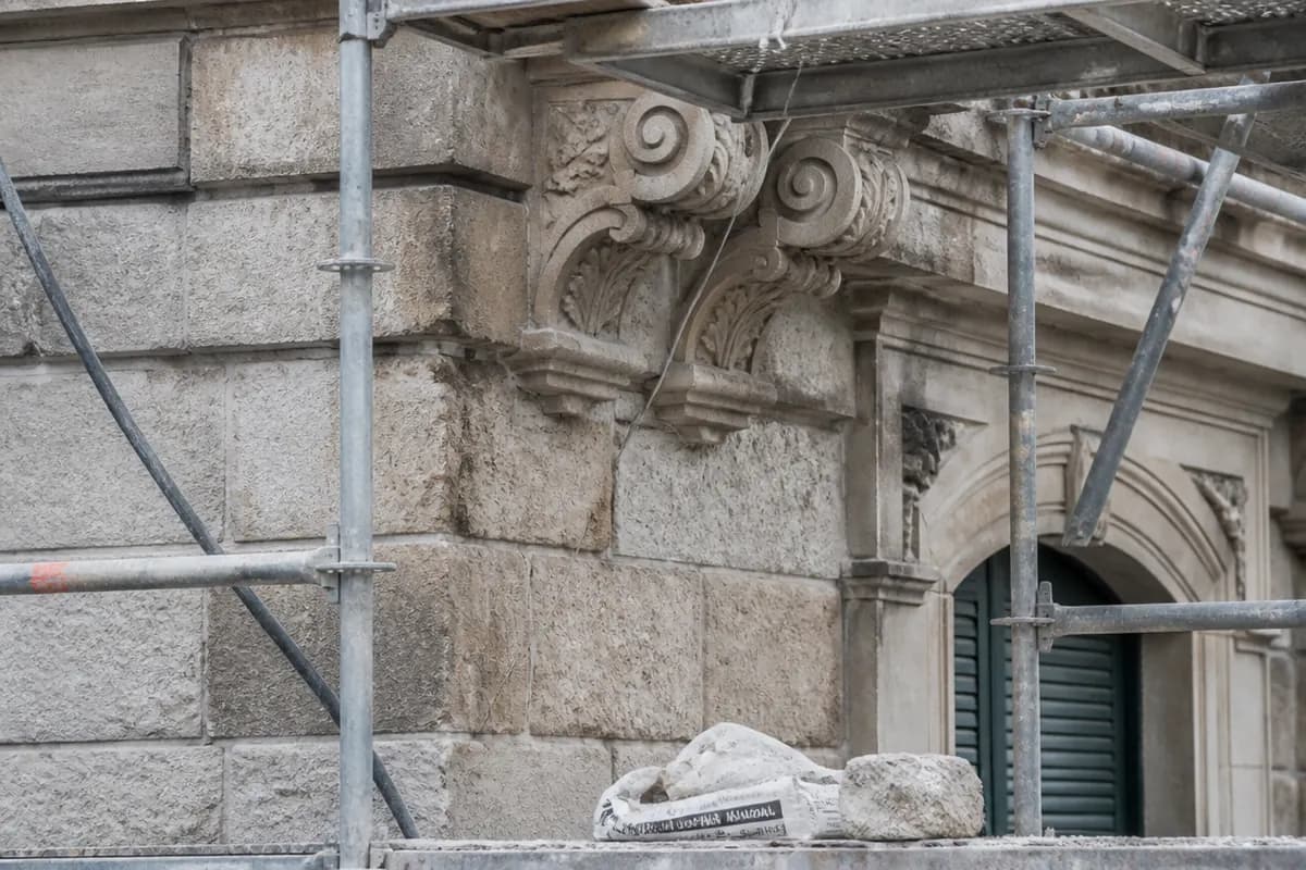 Detalle de fachada de piedra natural en restauración con andamiaje ligero y protecciones laterales